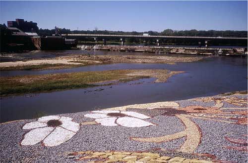 Photo of mural on levee in Lawrence; colored stones showing flowers in a quilt pattern.