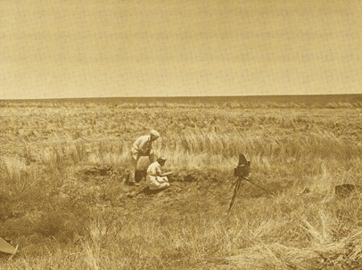 Old sepia photo; short grasses surrounding cleared area.