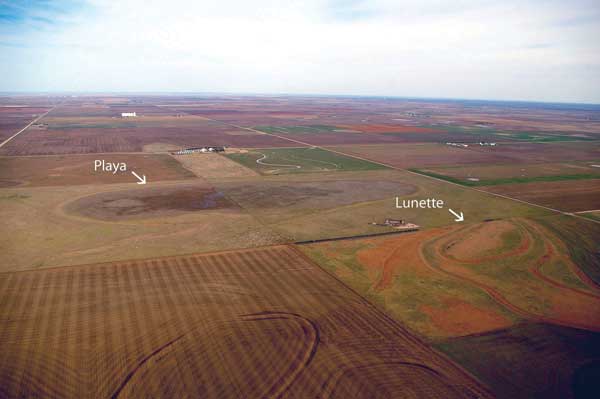 Aerial photo shows dry playa with serpentine mound of soil (the lunette) to the right of the playa.