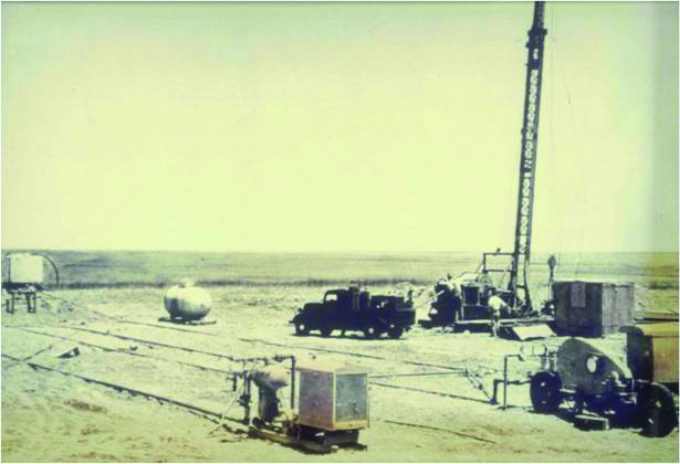 Old color photo of drill site in Hugoton field, 1947, showing first fracturing job.