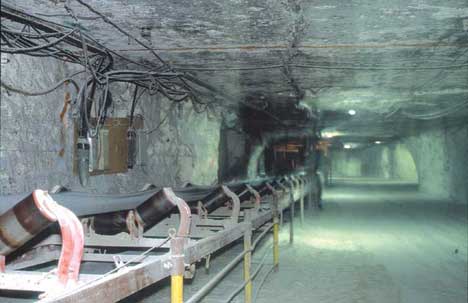 Converyor belt at side of rectangular tunnel in mine.